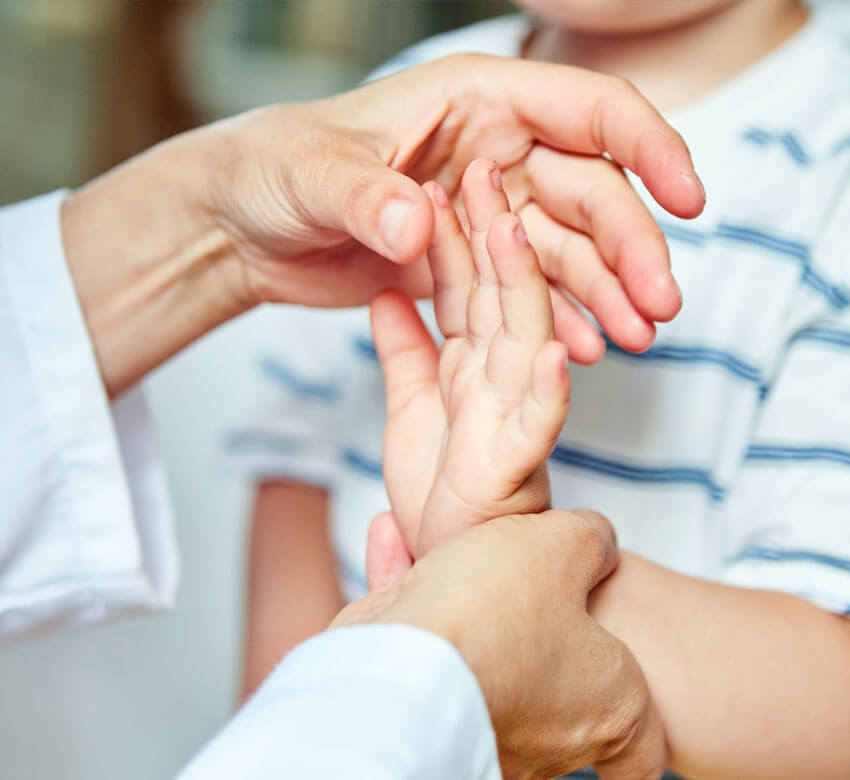 Pediatric hand being examined by doctor 