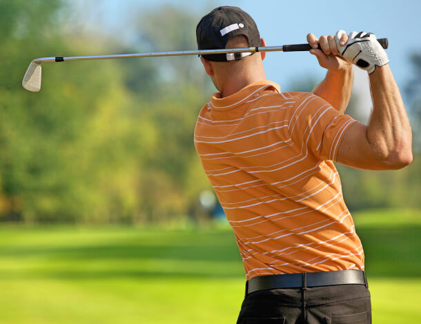Golfer in orange shirt after hitting shot