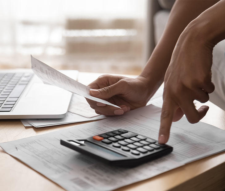 womans hands on desk with calculator and papers